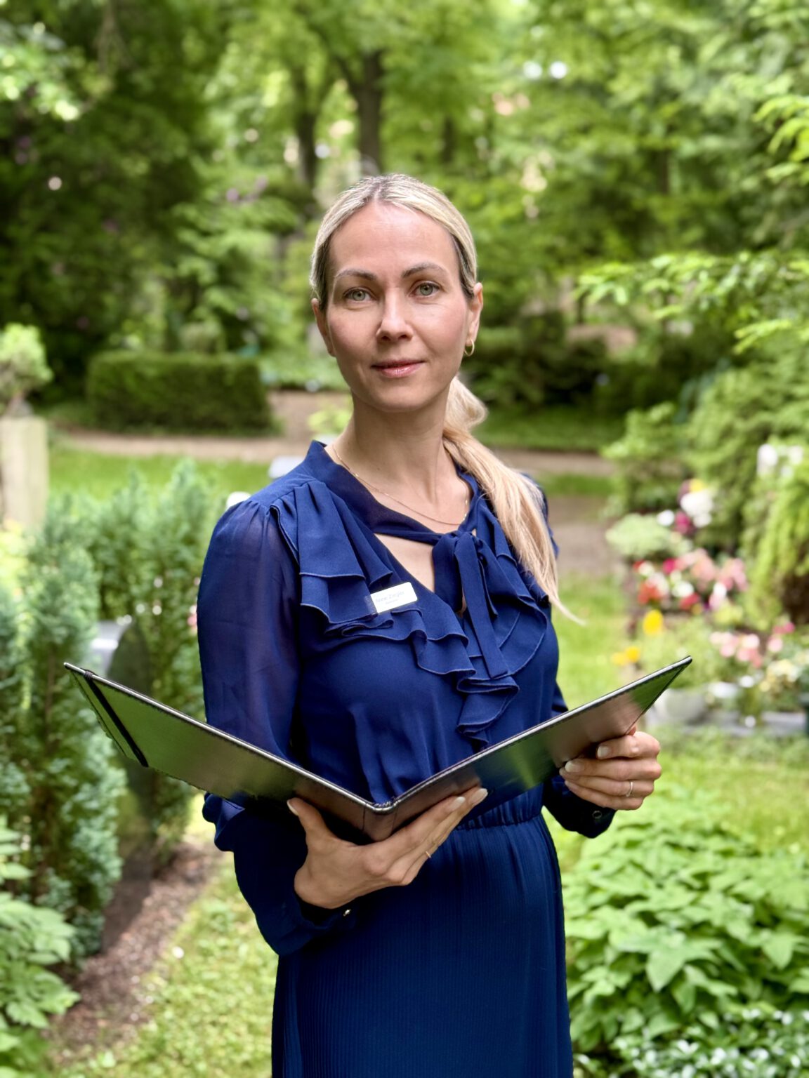Anne Ziegler, freie Rednerin in Dresden, mit Rednermappe in einem Garten